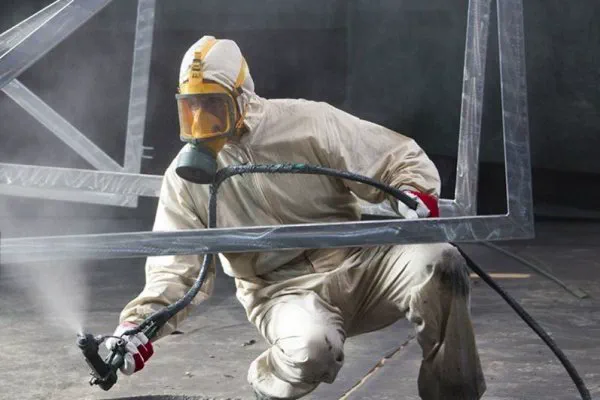 Mitarbeiter beim Pulverbeschichten von Metallkomponenten
